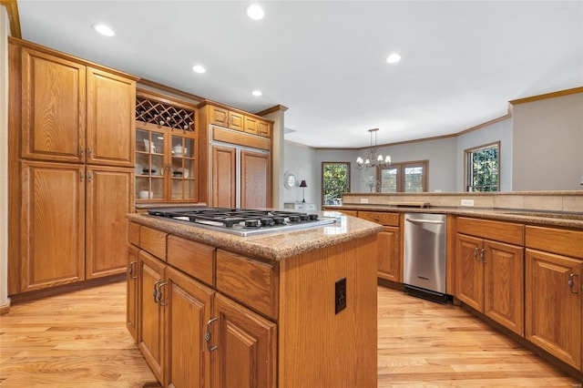 kitchen featuring light hardwood / wood-style flooring, pendant lighting, a chandelier, a kitchen island, and stainless steel gas cooktop