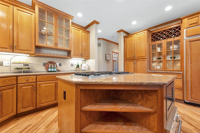 kitchen with a kitchen island, light wood-type flooring, stainless steel gas stovetop, and crown molding