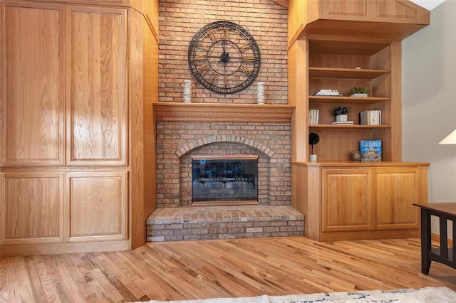 unfurnished living room with lofted ceiling, a fireplace, built in features, and light hardwood / wood-style flooring