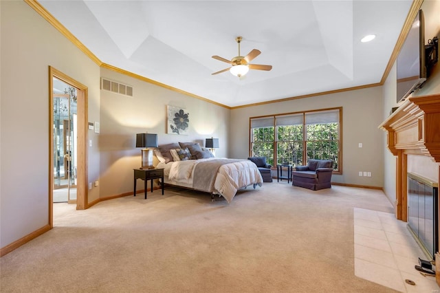 carpeted bedroom featuring ceiling fan, crown molding, a tiled fireplace, and a tray ceiling