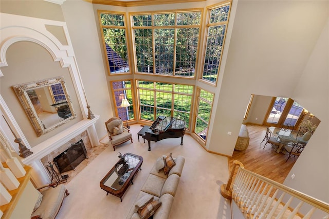 living room with a high ceiling, a tile fireplace, and wood-type flooring