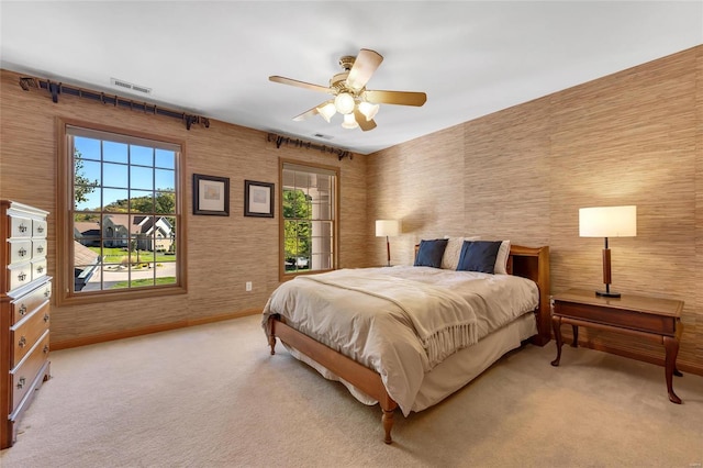 bedroom featuring light colored carpet, ceiling fan, and multiple windows