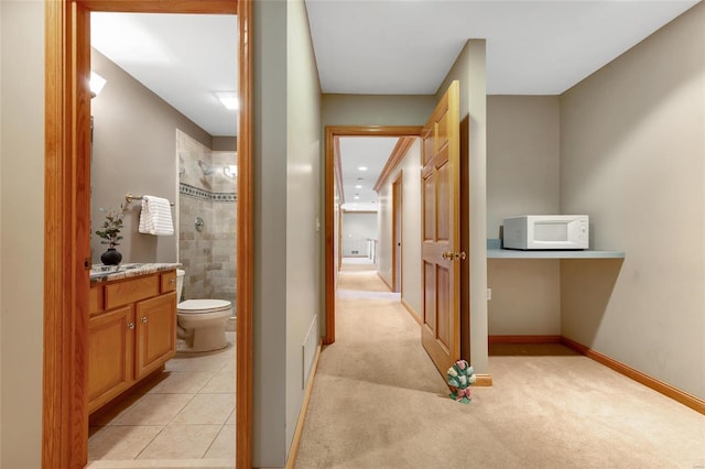 bathroom featuring a tile shower, vanity, and toilet