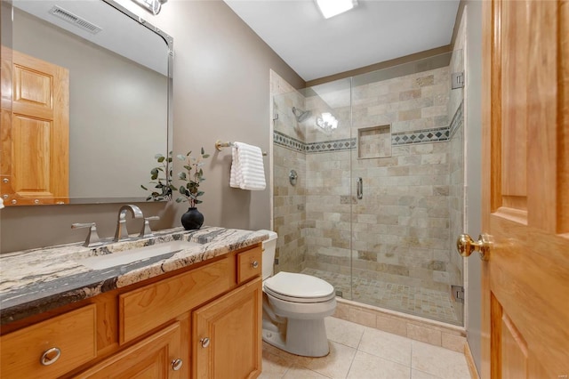 bathroom featuring toilet, tile patterned flooring, a shower with door, and vanity