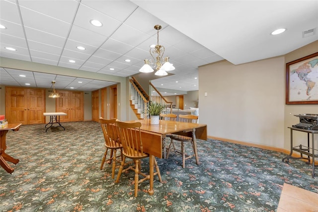 carpeted dining room featuring a notable chandelier and a paneled ceiling