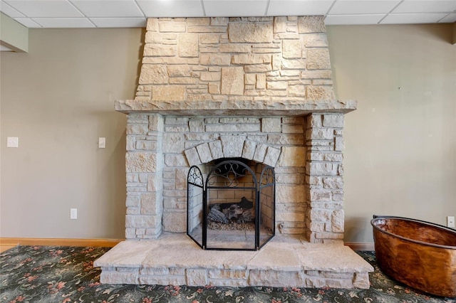 room details with a paneled ceiling and a stone fireplace