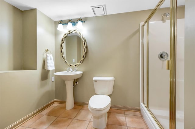 bathroom featuring toilet, a shower with door, and tile patterned floors