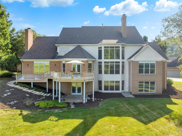 rear view of house with a deck, a patio area, and a lawn