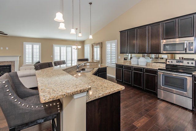 kitchen featuring a breakfast bar area, an island with sink, dark hardwood / wood-style floors, and appliances with stainless steel finishes