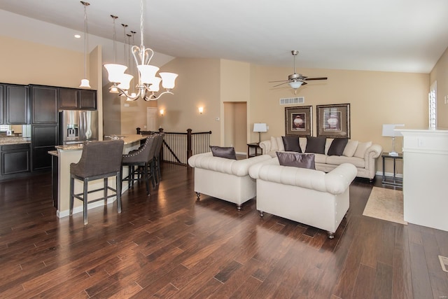 living room featuring ceiling fan with notable chandelier, dark wood-type flooring, and high vaulted ceiling