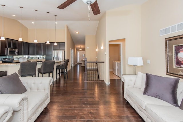 living room with dark hardwood / wood-style floors, ceiling fan, washing machine and dryer, and high vaulted ceiling