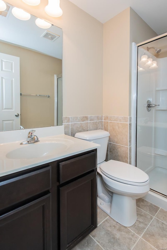 bathroom with tile patterned flooring, toilet, tile walls, and an enclosed shower