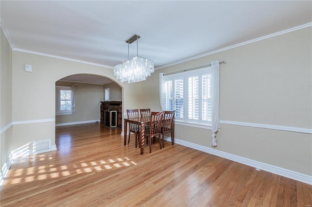 dining space with a chandelier, light wood-type flooring, a wealth of natural light, and crown molding