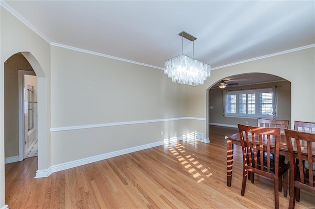 dining room featuring wood-type flooring, ceiling fan with notable chandelier, and ornamental molding