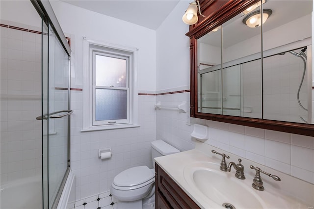 full bathroom featuring shower / bath combination with glass door, vanity, tile walls, and toilet