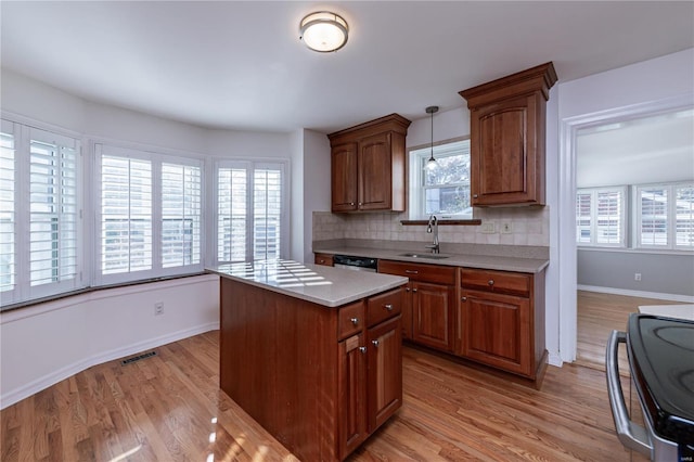 kitchen with decorative light fixtures, plenty of natural light, light hardwood / wood-style floors, and sink