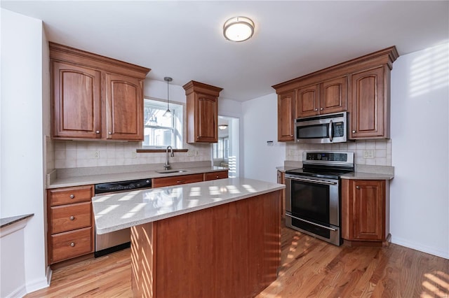 kitchen with sink, pendant lighting, light hardwood / wood-style floors, decorative backsplash, and appliances with stainless steel finishes