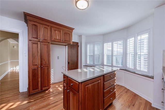 kitchen with light stone counters, light hardwood / wood-style flooring, and a center island