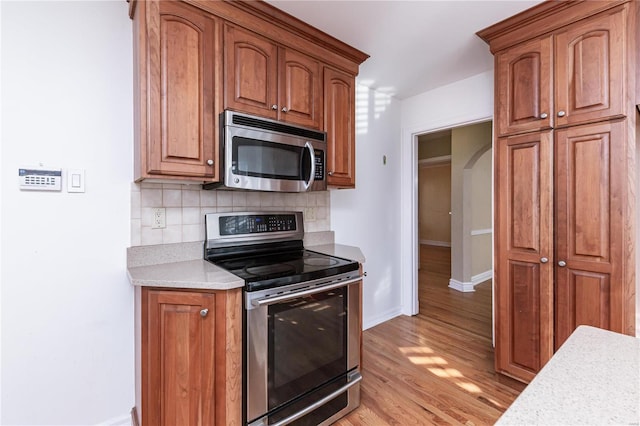 kitchen with decorative backsplash, light hardwood / wood-style floors, and appliances with stainless steel finishes