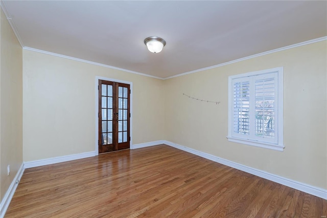 empty room with crown molding, french doors, and light wood-type flooring