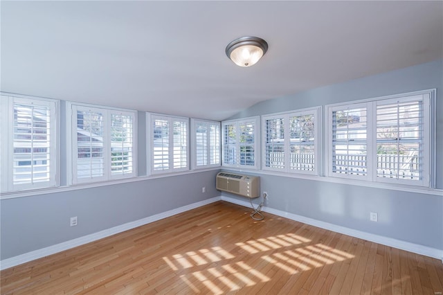 unfurnished sunroom with a wall unit AC and lofted ceiling