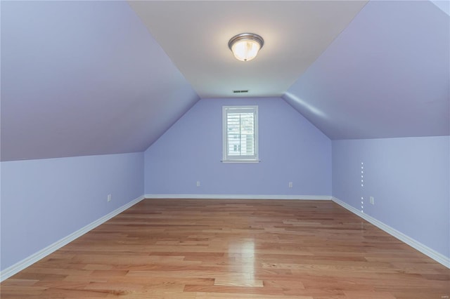 additional living space with light wood-type flooring and vaulted ceiling