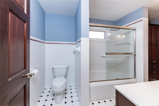 full bathroom featuring shower / bath combination with glass door, vanity, tile walls, and toilet