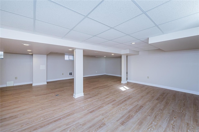 basement featuring a paneled ceiling and light wood-type flooring