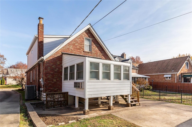 back of property with central AC and a sunroom