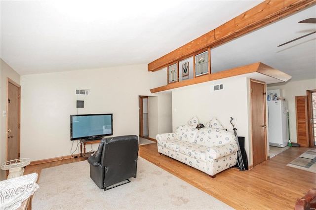 bedroom with hardwood / wood-style floors, beam ceiling, and white refrigerator