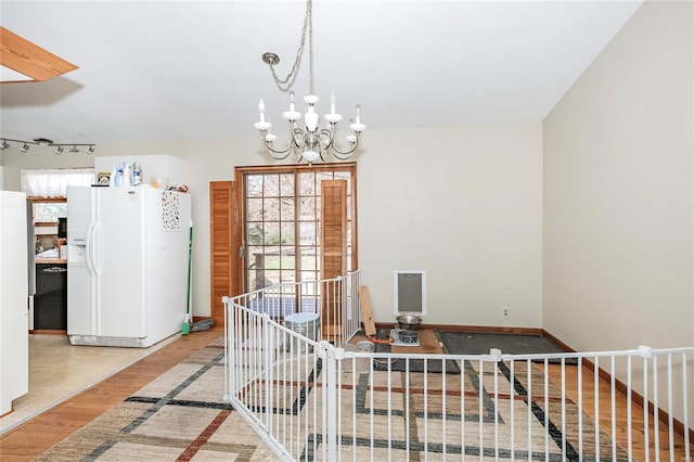 unfurnished dining area featuring light hardwood / wood-style flooring and an inviting chandelier