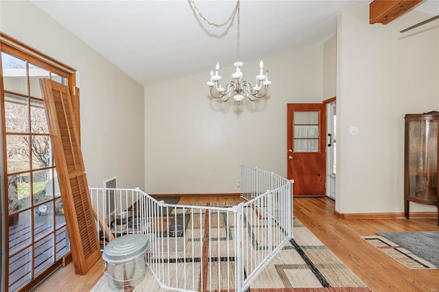 interior space with vaulted ceiling with beams, a wealth of natural light, a notable chandelier, and light wood-type flooring