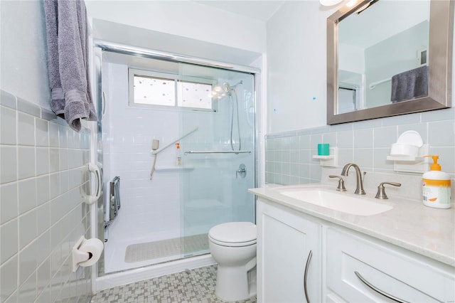 bathroom with vanity, toilet, an enclosed shower, and tile walls