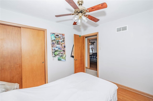 bedroom with ceiling fan, light hardwood / wood-style floors, and a closet