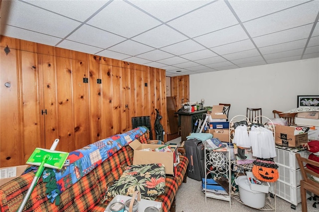 bedroom featuring wooden walls, a drop ceiling, and carpet