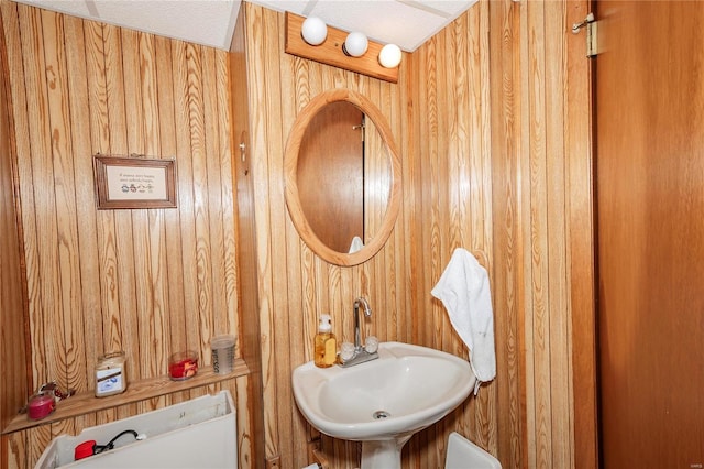 bathroom with sink, a textured ceiling, and wooden walls