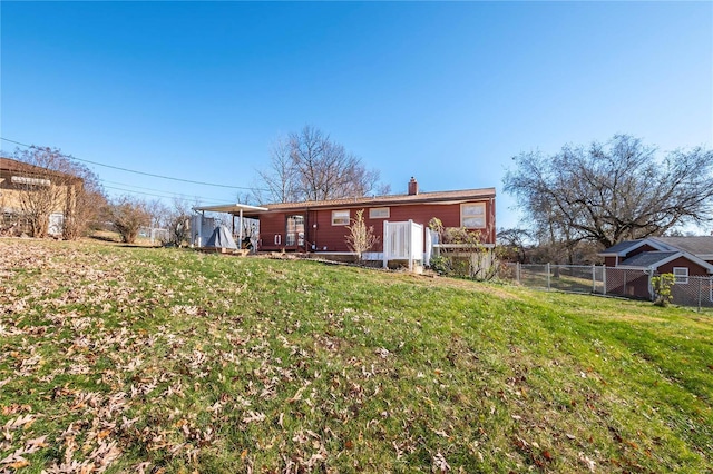 rear view of property with a carport and a lawn