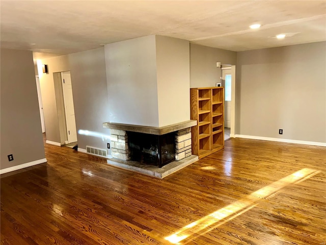 unfurnished living room featuring a stone fireplace and hardwood / wood-style floors