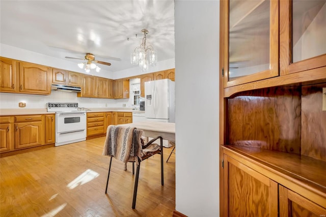 kitchen with ceiling fan with notable chandelier, white appliances, hanging light fixtures, and light hardwood / wood-style flooring