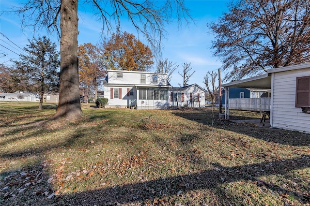 rear view of house with a lawn and a sunroom