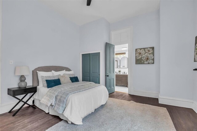 bedroom featuring connected bathroom, a closet, dark wood-type flooring, and ceiling fan