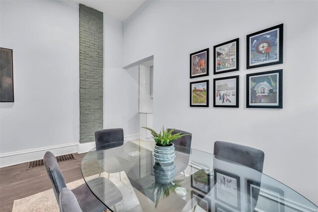 dining space featuring wood-type flooring and a towering ceiling