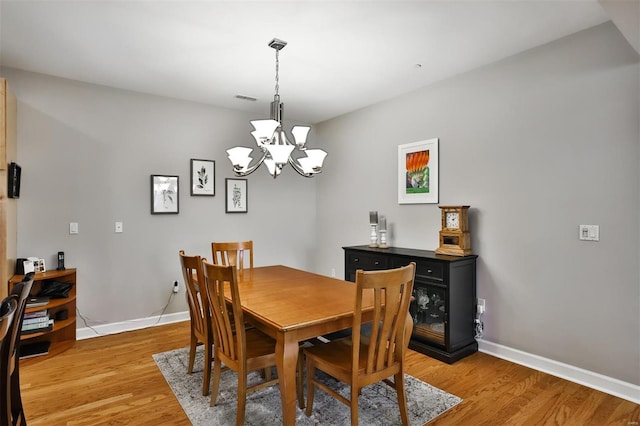 dining area featuring hardwood / wood-style floors and an inviting chandelier