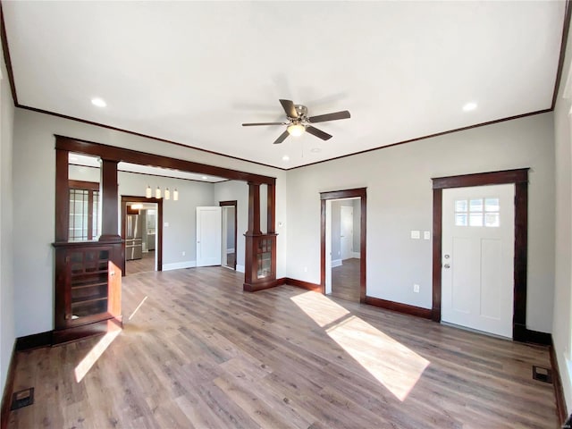 unfurnished living room with wood-type flooring, ornate columns, ceiling fan, and ornamental molding