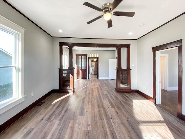 unfurnished living room featuring ornate columns, ceiling fan, plenty of natural light, and hardwood / wood-style flooring