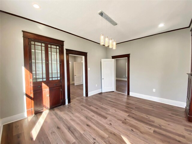 unfurnished dining area with crown molding, an inviting chandelier, and hardwood / wood-style flooring