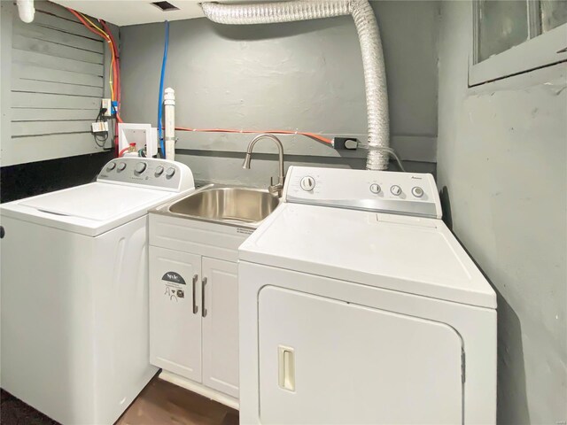 clothes washing area featuring washing machine and clothes dryer, sink, and cabinets