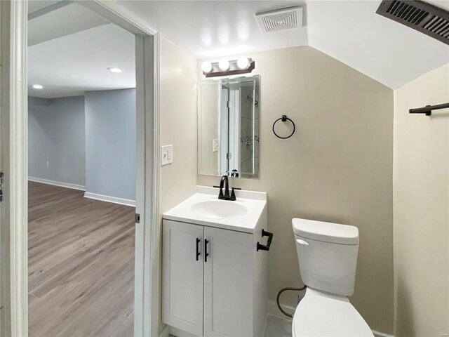 bathroom featuring hardwood / wood-style floors, vanity, vaulted ceiling, and toilet