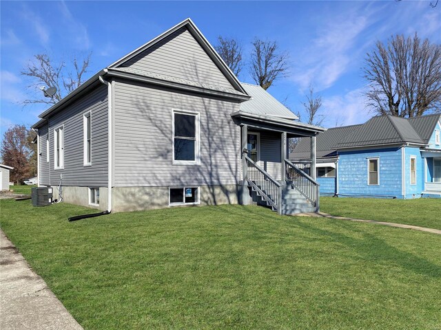 view of front facade featuring a front yard, cooling unit, and covered porch