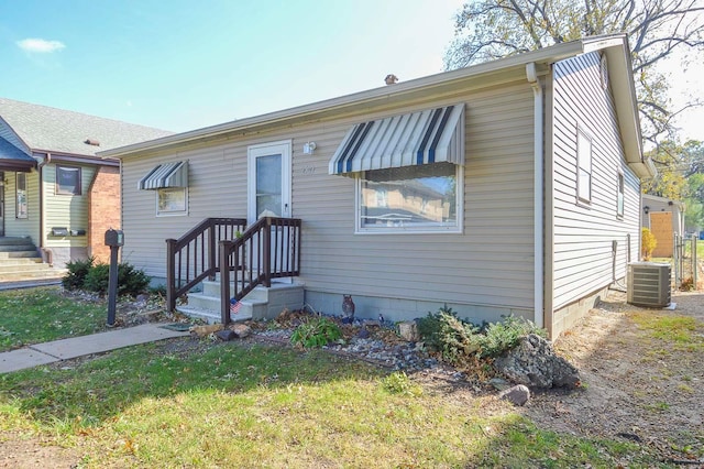 view of front of property with cooling unit and a front yard